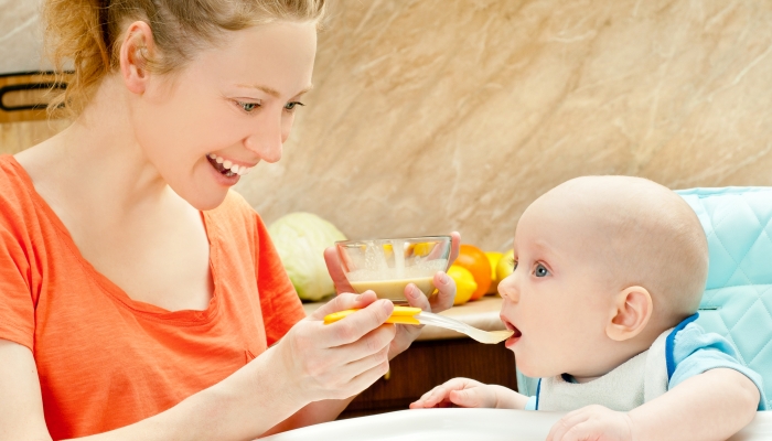 Mother spoon-feeds her child.