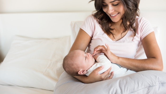 Mother with baby in a boppy pillow.