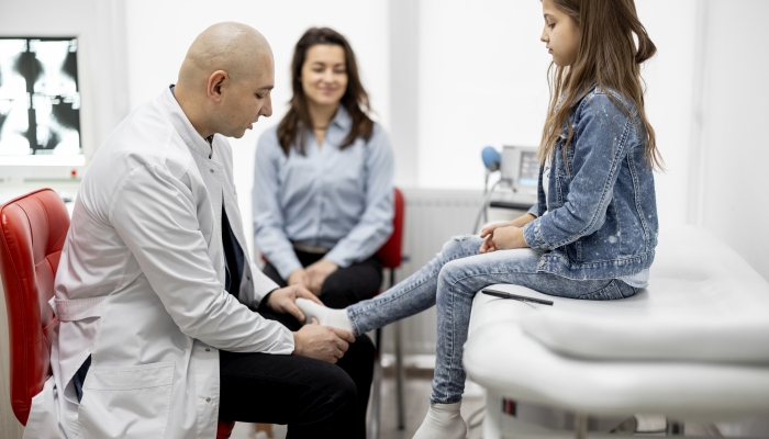 Physical therapist talking with a little girl and her mom during medical appointment at the office.