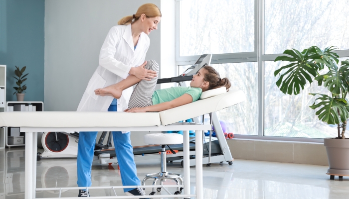 Physical therapist working with little girl in rehabilitation center.