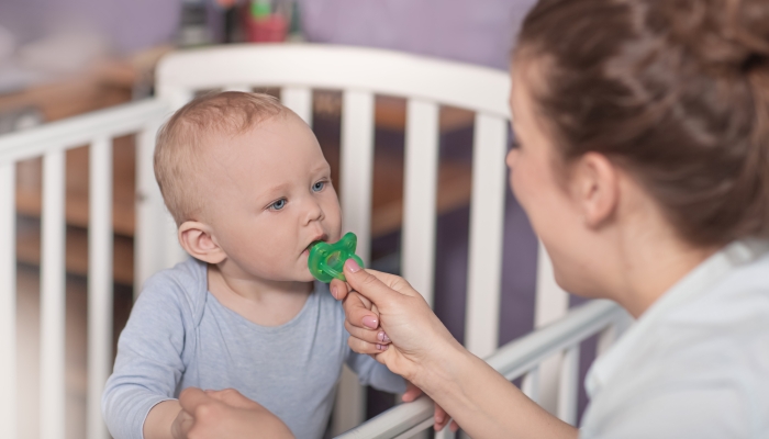 Portrait of a child to whom the mother offers a pacifier.