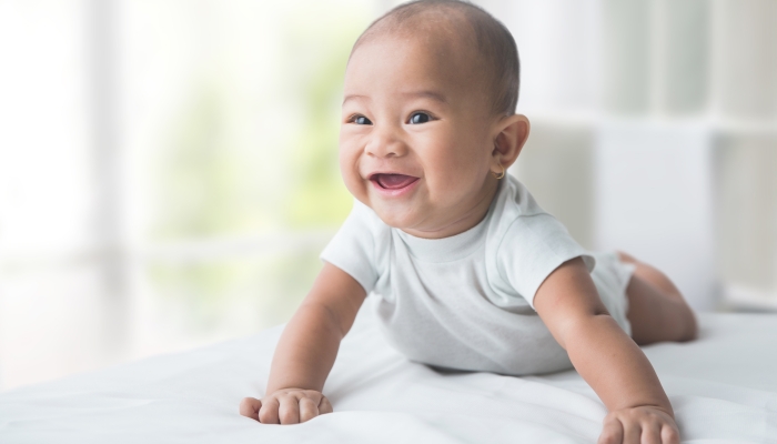 Smiling happy baby while tummy time at home.