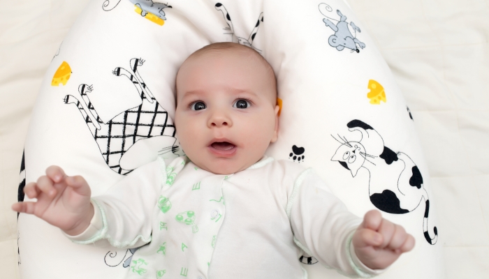 Surprised baby boy in a boppy pillow.