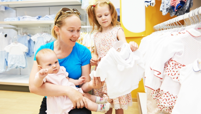 Woman with baby and child in clothes shop.