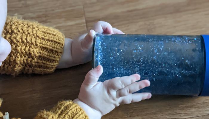 Small child holding blue sensory bottle.