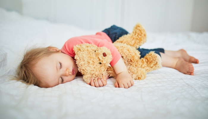 Adorable baby girl sleeping with her favorite toy.