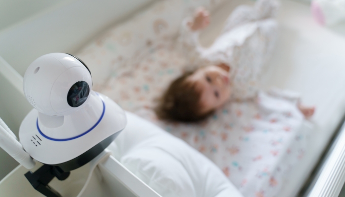 Baby monitor on baby bed at home in bedroom watching small child in cradle while sleeping.