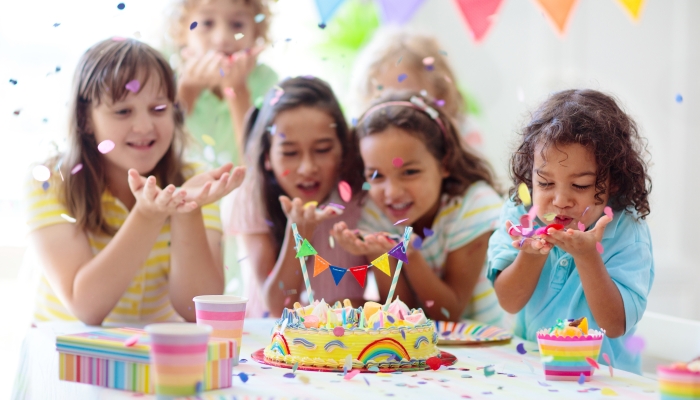 Children celebrate with colorful cake and gifts.