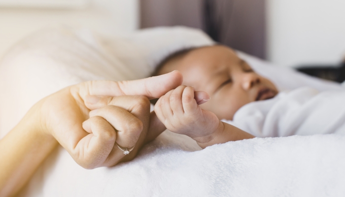 Close up of hands baby newborn holding mom finger.