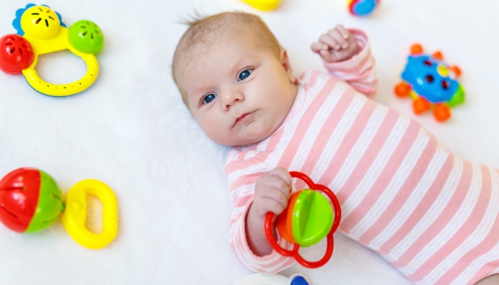 Cute adorable newborn baby holding a toy.