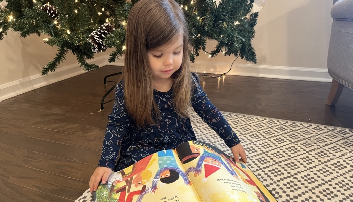 Cute little girl reading christmas book.