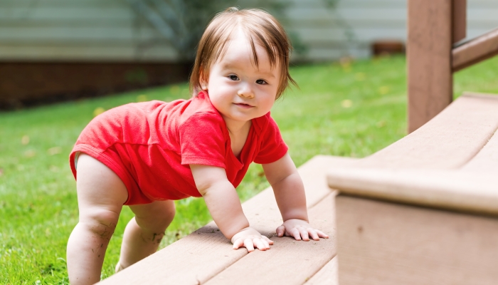 Happy baby boy climbing the backyard stairs.