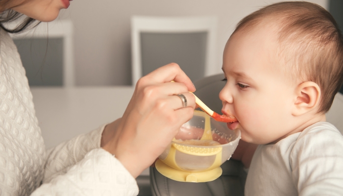 Mom feeding her baby girl with a spoon.