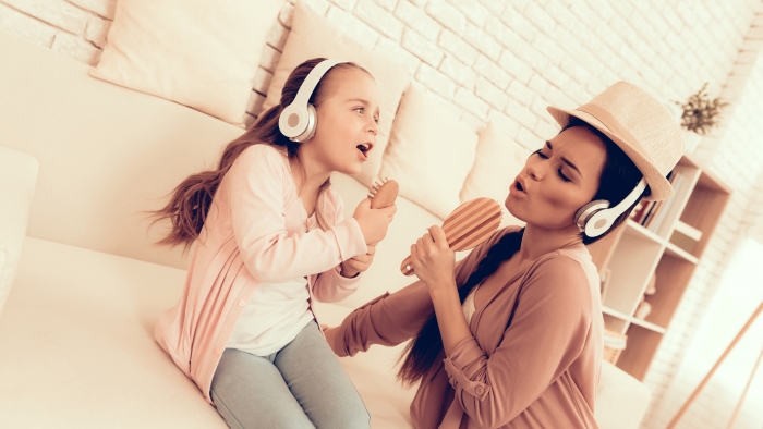 Mother and daughter in headphones singing at home.