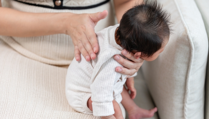 Mother take care her newborn baby hiccups to burp the baby may reduce air in stomach.