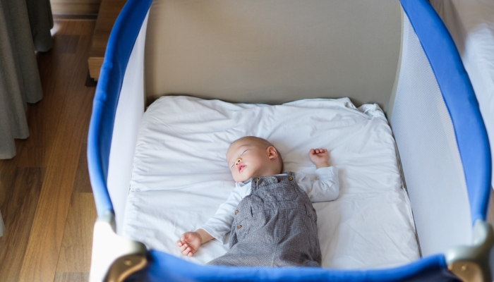 Peaceful kid lying on a pack n play while sleeping.