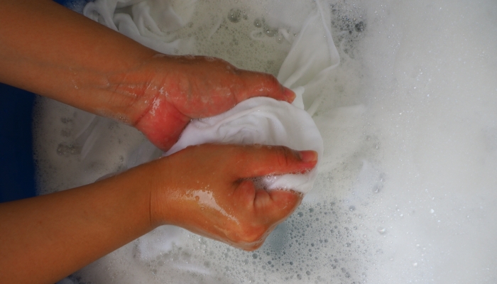 Top image washing white diaper with woman's hand.
