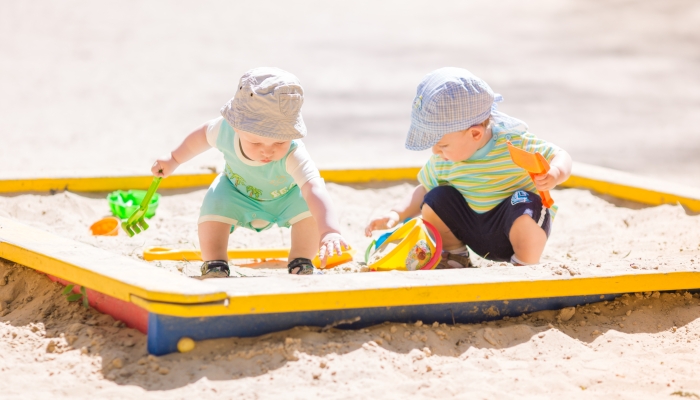 Two baby boys playing with sand.