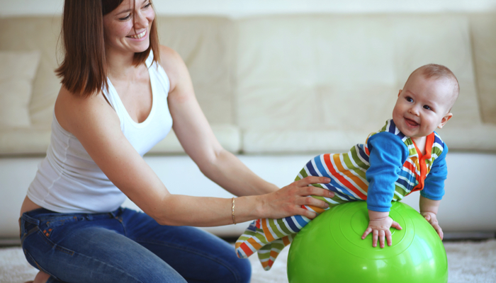 Mother holding her baby on a small exercise ball.