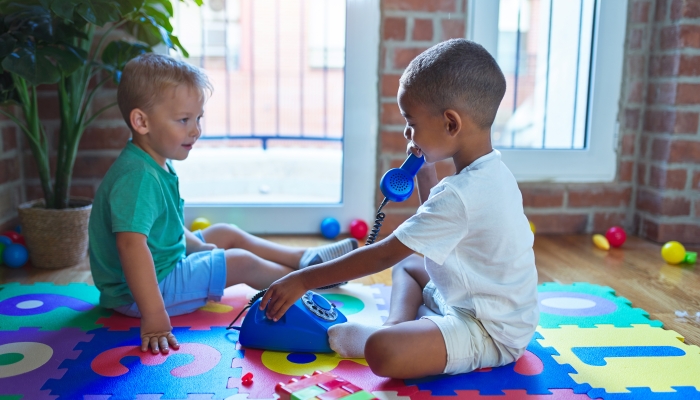 Adorable toddlers playing around lots of toys at kindergarten.