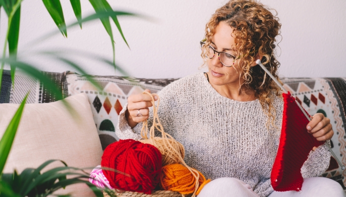 Adult attractive woman at home in knitting work activity using colorful wool.