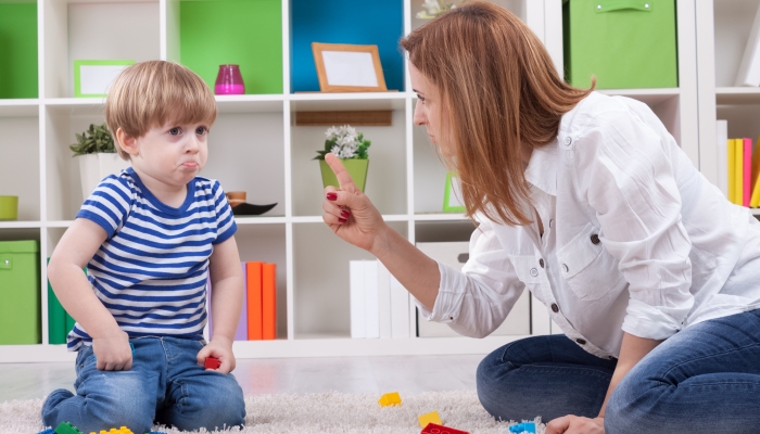 Angry mother scolding a toddler not listening to her.