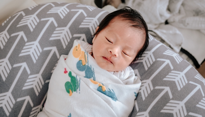 Asian baby boy sleeping on nursing pillow at sweet home.