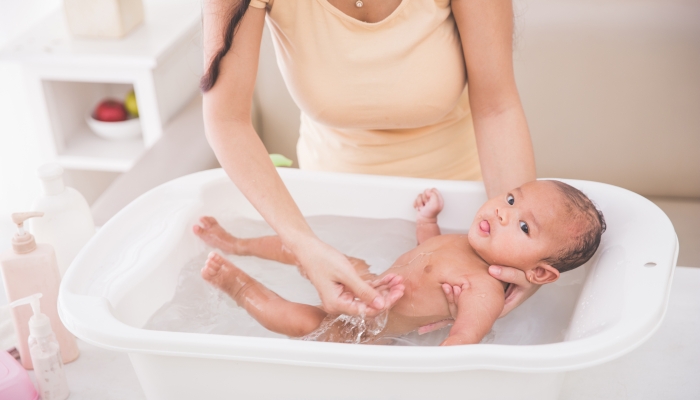 Baby is being bathed by his mother.