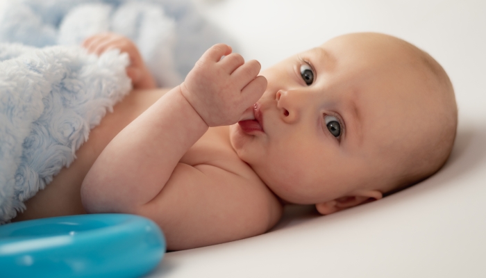 Baby sucking his thumb on white background.