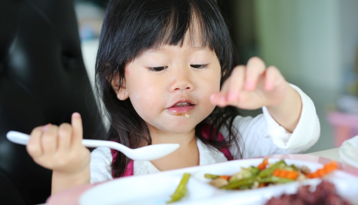 Cute asian kid girl age about 2 years old eating rice by self.