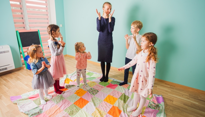 Female teacher and preschool pupils having fun together.