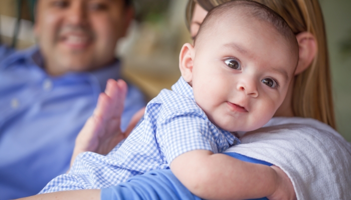 Happy Attractive Mixed Race Couple Burping Their Son.