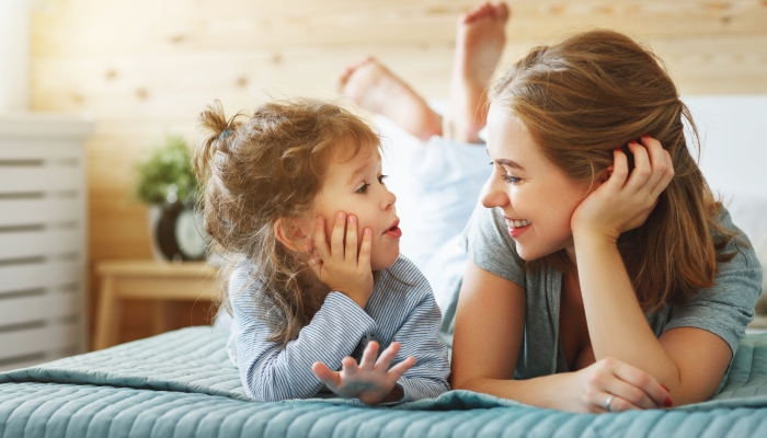 Happy family mother and child daughter play and laughing in bed.