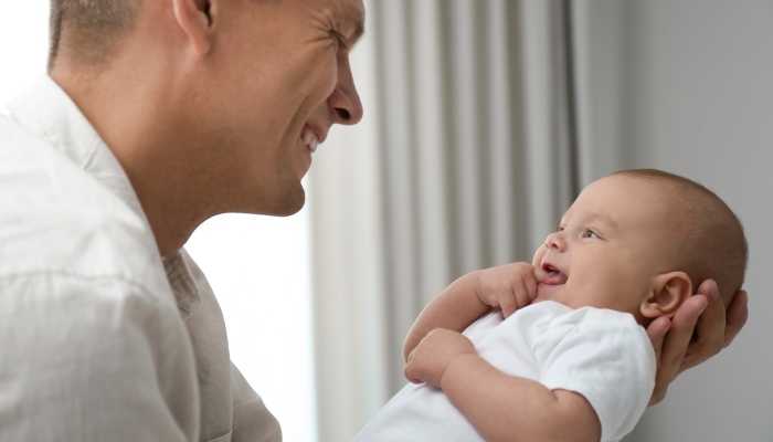 Happy father holding his babling cute baby at home.