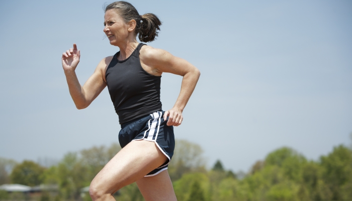 Mature woman running outdoors in the park.