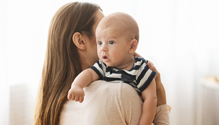 Mother patting adorable baby on back after breasfeeding.