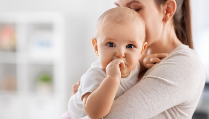 Mother with little baby daughter teething at home.