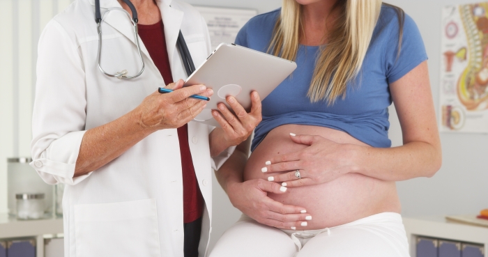 Pregnant woman and doctor in office.