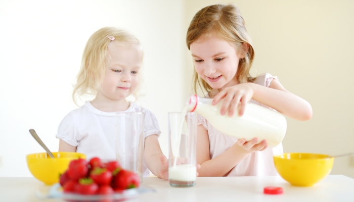 Sisters eating cereal with milk.