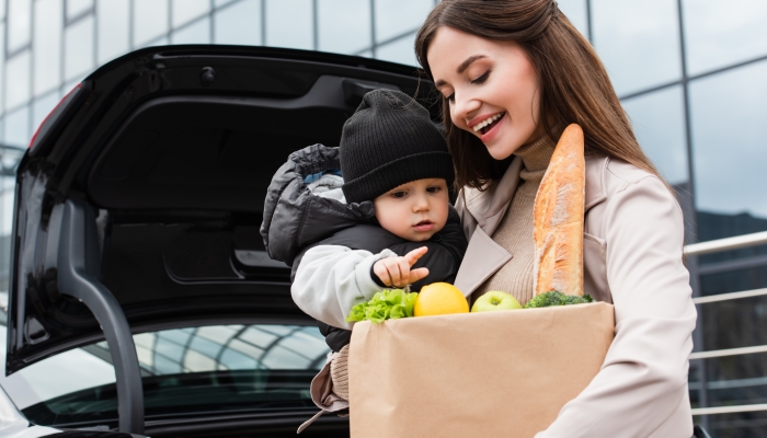 Toddler boy pointing at fresh food in shopping bag.