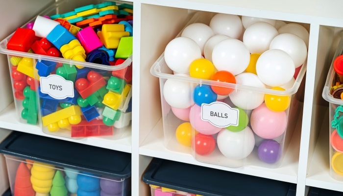 Transparent plastic containers with various children's toys on shelves.