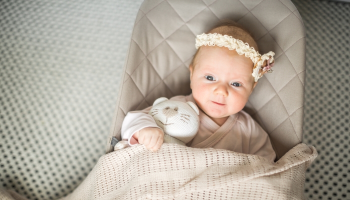 a small child with a toy in a cocoon, a baby in a lounger.