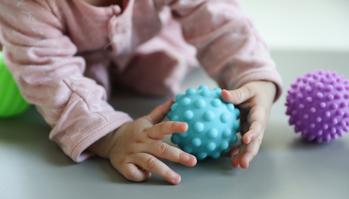 Baby reaching for sensory toys.