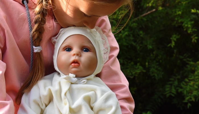 Child girl hugs her favorite doll.