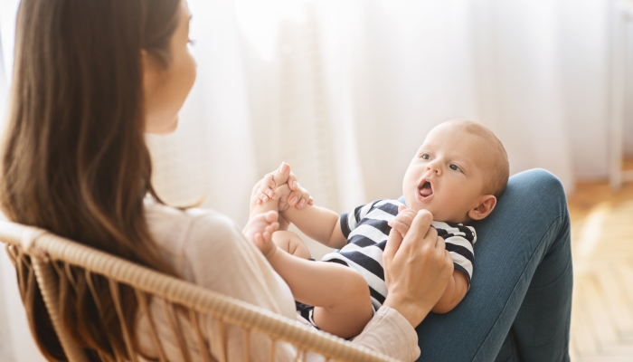 Cute little baby lying on mother's lap and cooing.