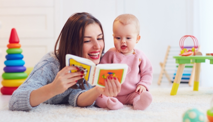 Cute mother and daughter playing together, reading first book.