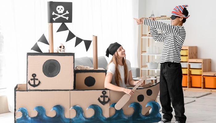 Little boy and his sister dressed as pirates playing with spyglass at home.