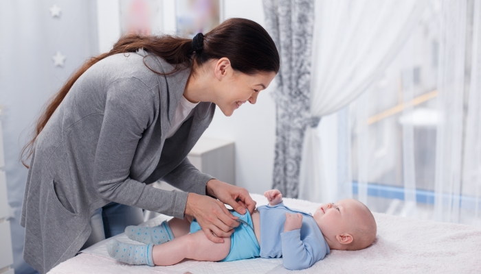 Mom changes a cloth diaper to a baby on a changing table.