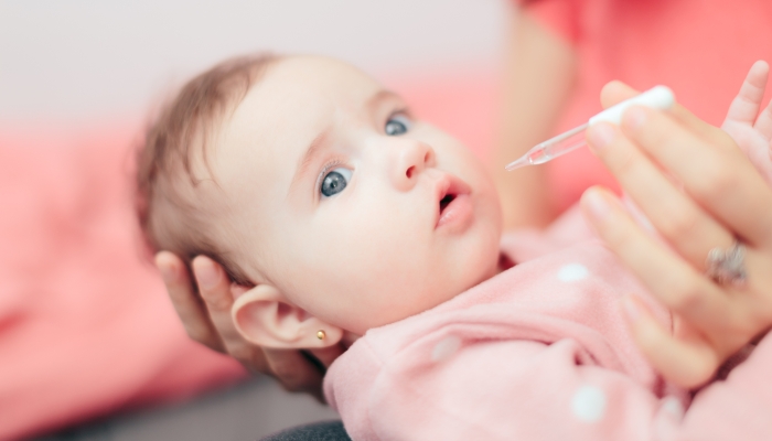 Mother administrating probiotic to her baby.