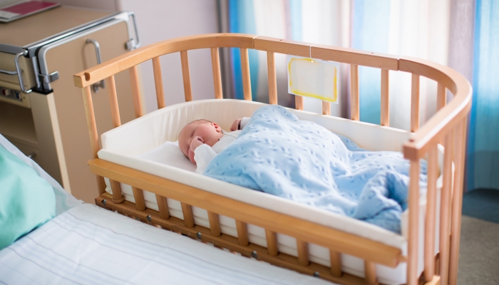 New born child in wooden co-sleeper crib.